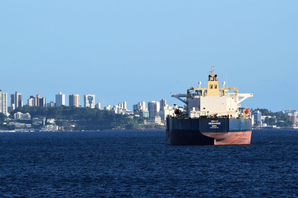 A cargo ship anchored in Salvador, Brazils harbor with the city skyline in the backdrop.